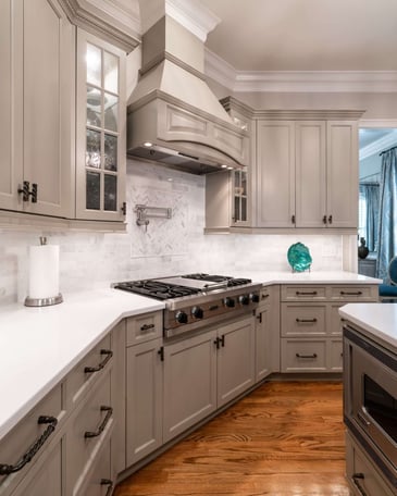 A bright remodeled kitchen with white cabinets and stainless steel gas range.