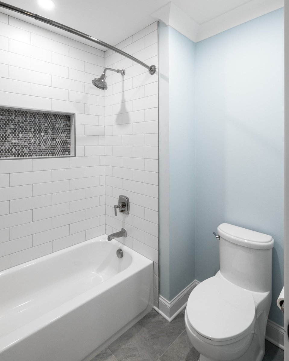 bathroom with white subway tile tub shower blue walls and gray tile floor in a custom home in charlotte nc