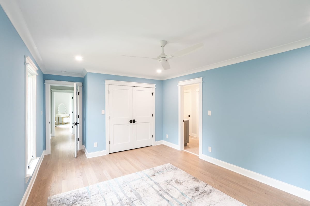 blue bedroom with hardwood floors white double doors and multiple tall windows in a custom home in charlotte nc