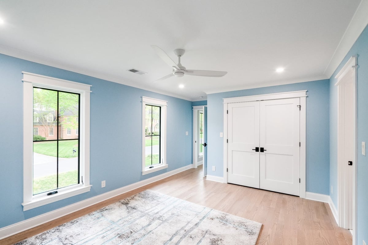 bright blue bedroom with hardwood floors white trim and double closet doors in a custom home in charlotte nc