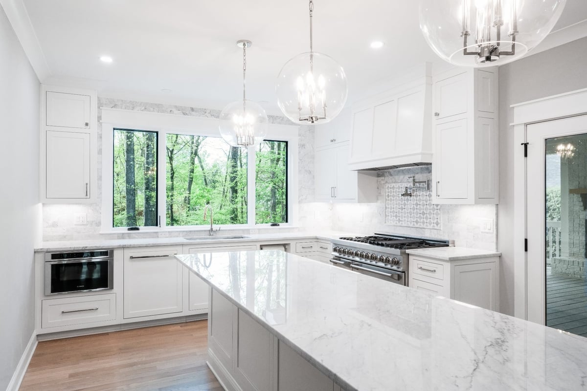 bright white kitchen with marble island professional range and forest views in a custom home in charlotte nc