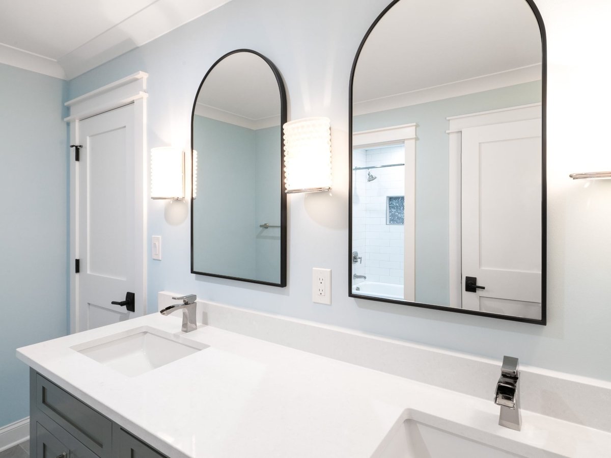 double vanity bathroom with arched black mirrors blue walls and white countertops in a custom home in charlotte nc