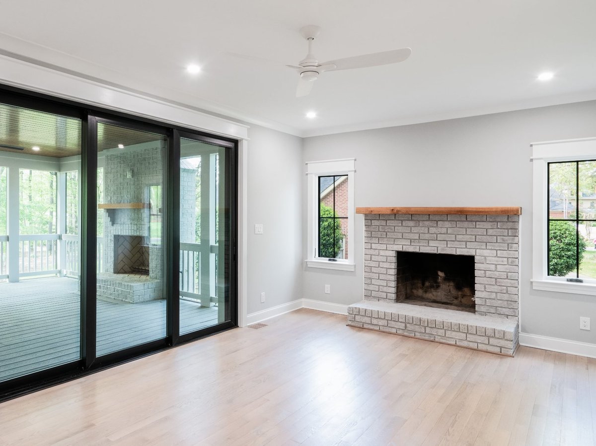 light filled living room with gray brick fireplace hardwood floors and screened porch in a custom home in charlotte nc