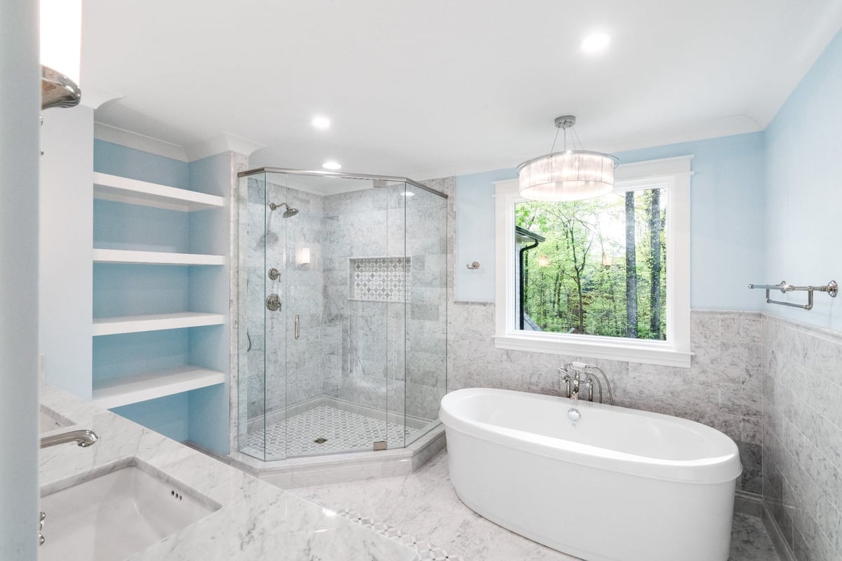 primary bathroom with marble glass shower freestanding tub and wooded view in a custom home in charlotte nc