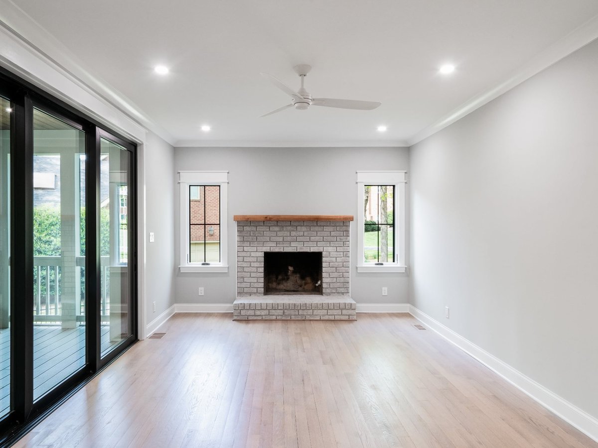 spacious living room with gray brick fireplace black sliding doors and hardwood floors in a custom home in charlotte nc
