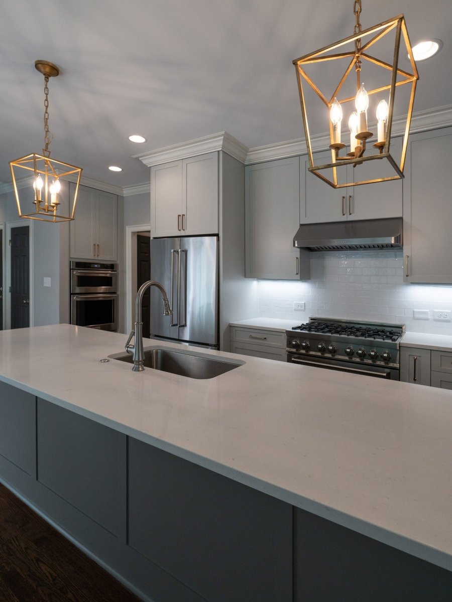 charlotte nc home project kitchen with gray cabinets stainless appliances white backsplash and brass pendants
