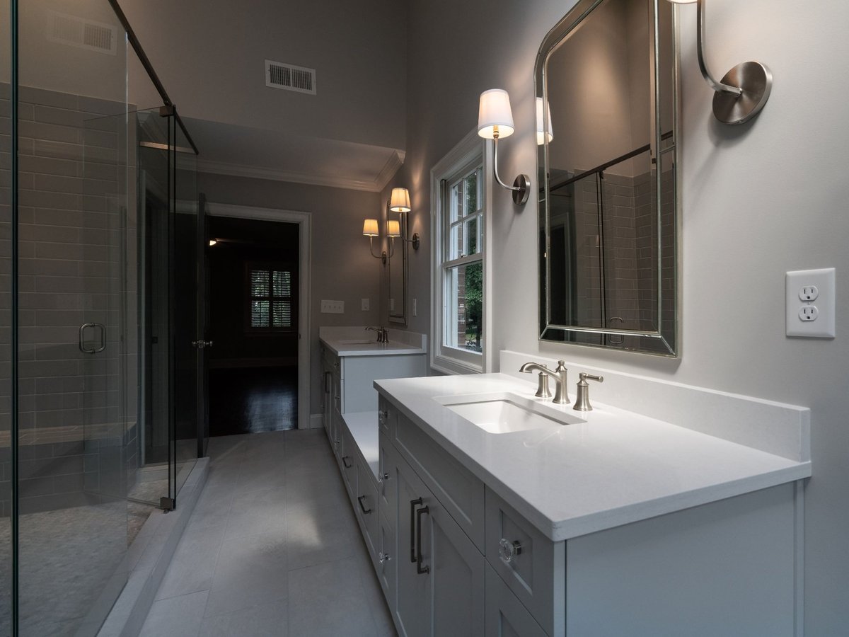 charlotte nc home project primary bathroom with double gray vanities quartz counters mirrors and glass shower