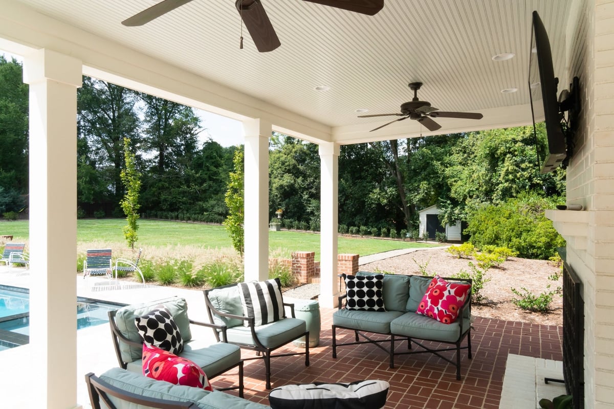 covered custom home pool house patio with brick floor outdoor seating and backyard view in charlotte nc