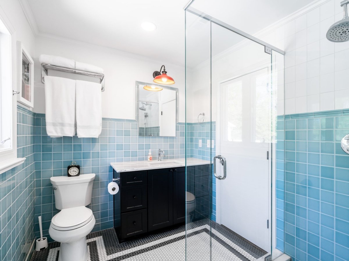 custom home bathroom with glass shower rainfall showerhead blue tile walls and black and white hex floor in charlotte nc