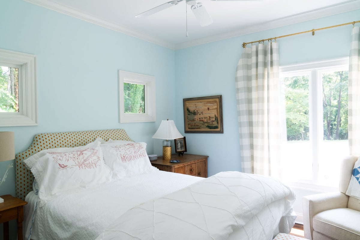 custom home bedroom with upholstered headboard white bedding and blue walls in charlotte nc