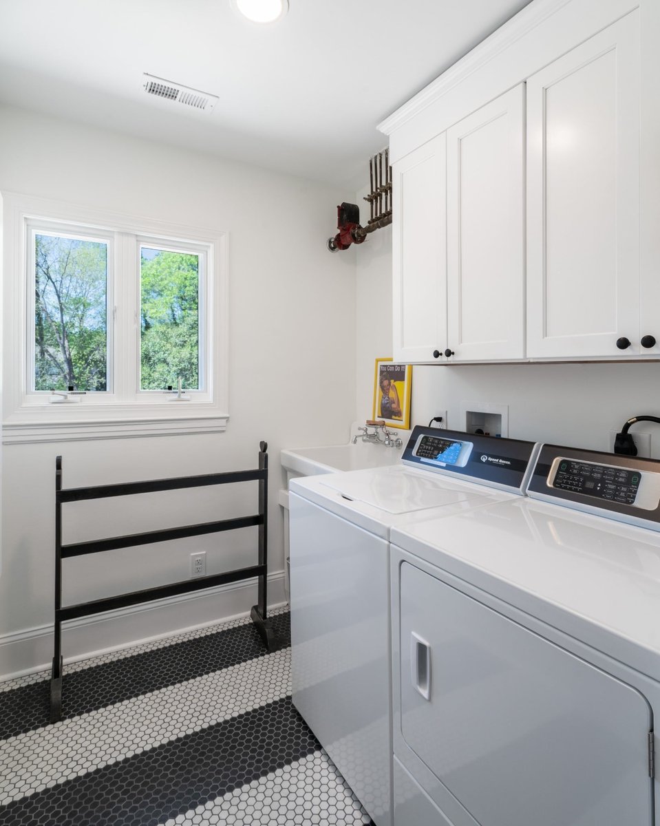 custom home laundry room with white washer dryer cabinetry utility sink and black and white hex tile floor in charlotte nc