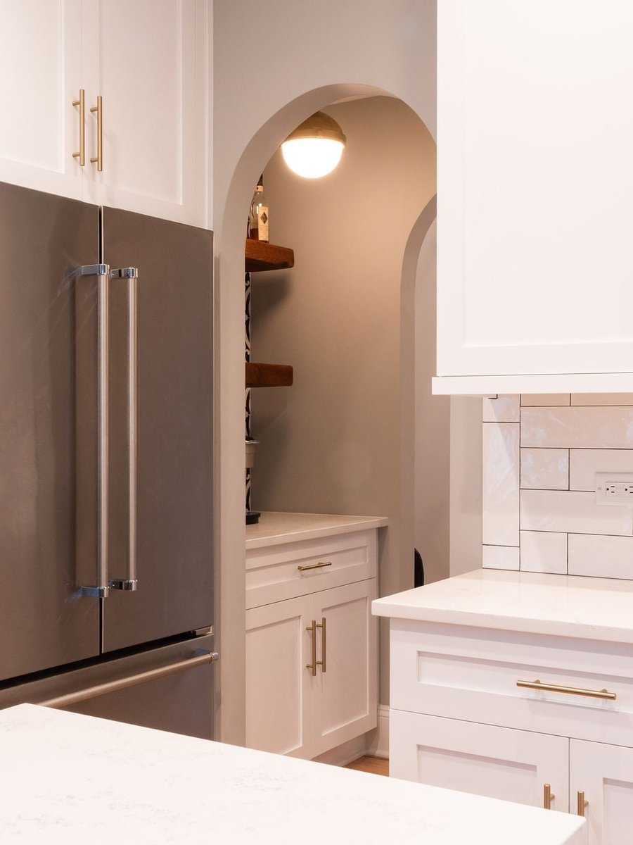 arched pantry entry beside stainless refrigerator and white cabinetry in a first floor remodel in fort mill sc