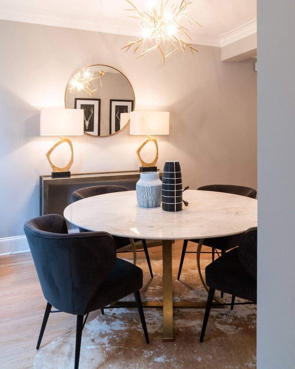 dining room with marble table dark chairs gold lighting and round mirror in a first floor remodel in fort mill sc