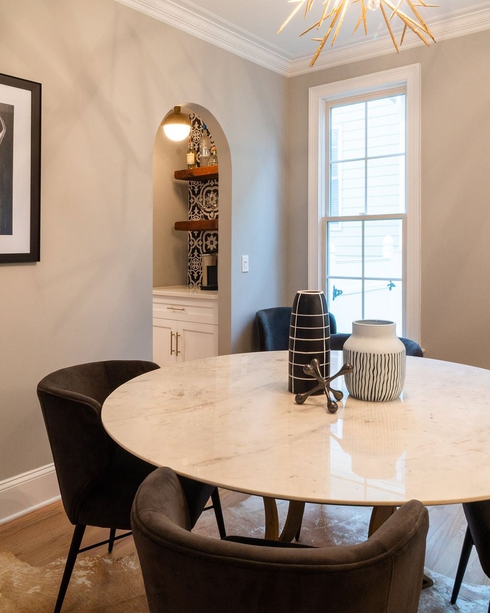 dining room with round stone table dark chairs and arched beverage station in a first floor remodel in fort mill sc