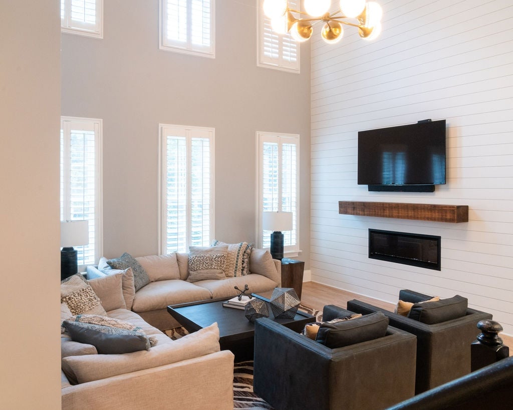 two story living room with sectional sofas dark chairs and modern fireplace in a first floor remodel in fort mill sc