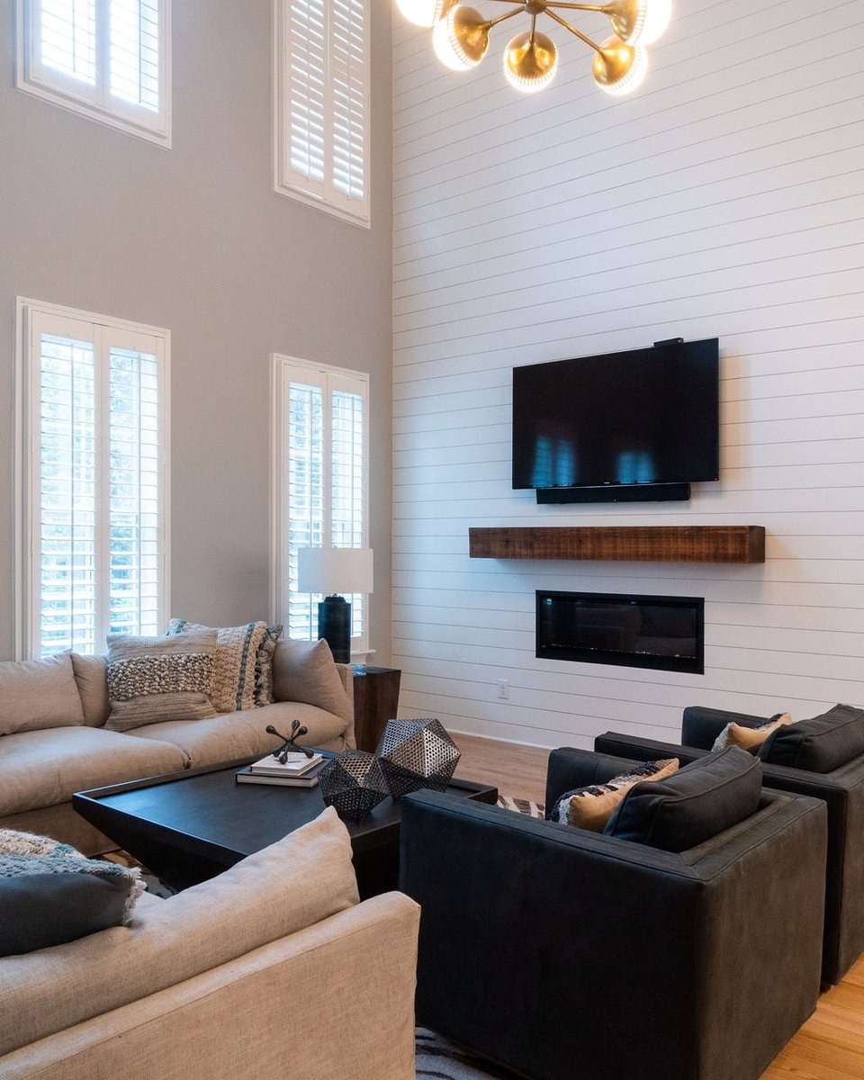 two story living room with shiplap fireplace wall sectional and dark armchairs in a first floor remodel in fort mill sc