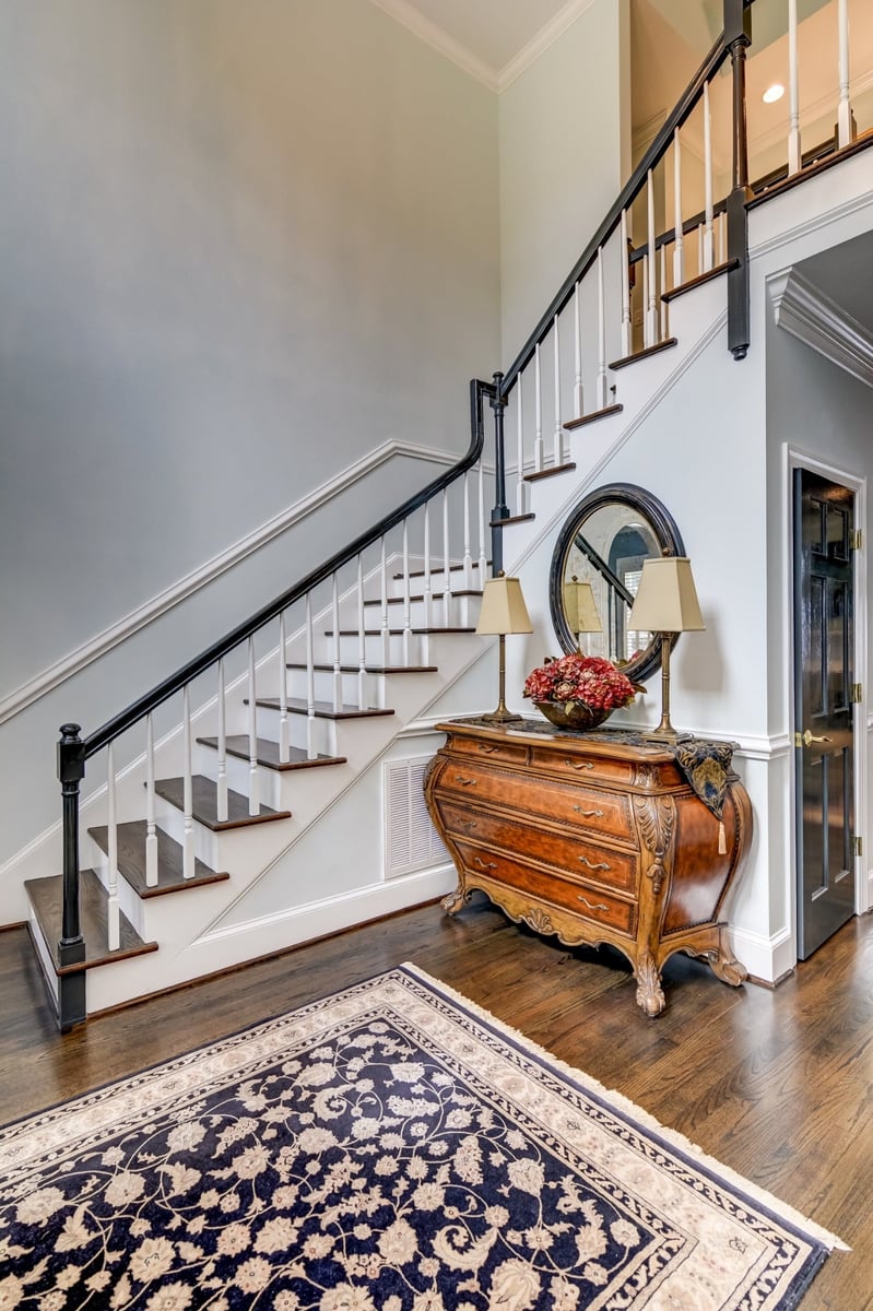foyer staircase with dark wood handrail antique chest and round mirror in charlotte nc whole home remodel