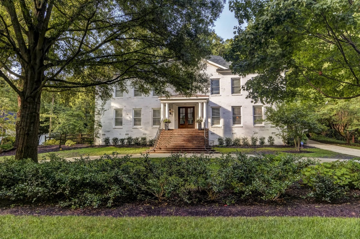 white brick home front facade framed by mature trees in charlotte nc whole home remodel