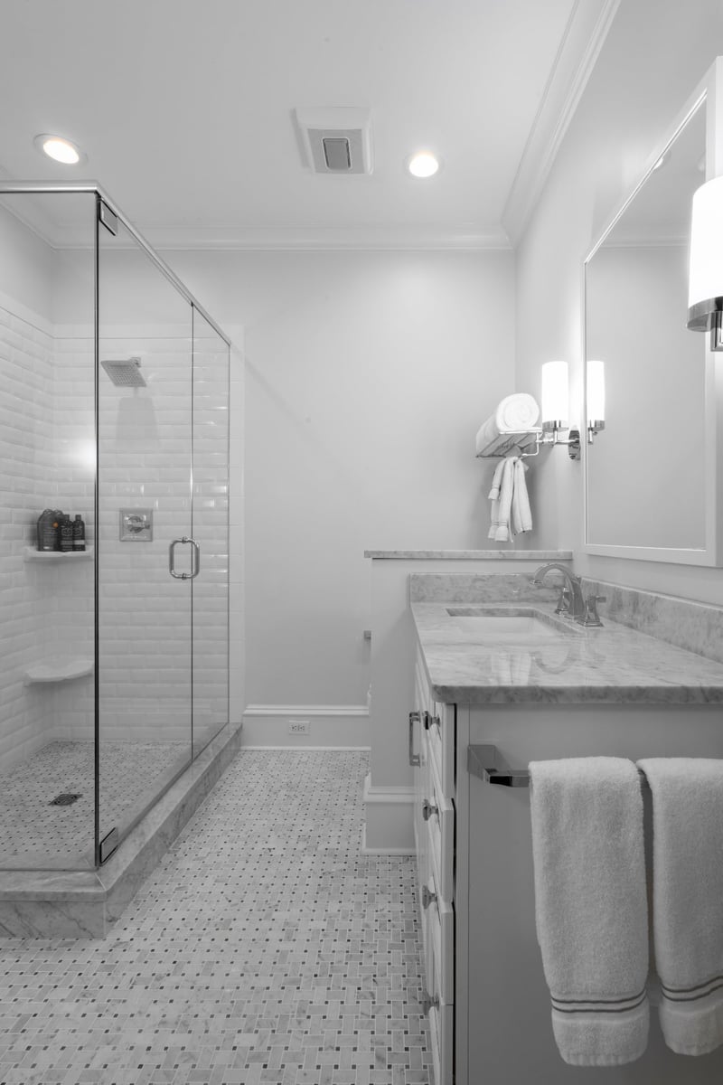white bathroom vanity with marble countertop glass shower and chrome sconces in charlotte nc whole home remodel