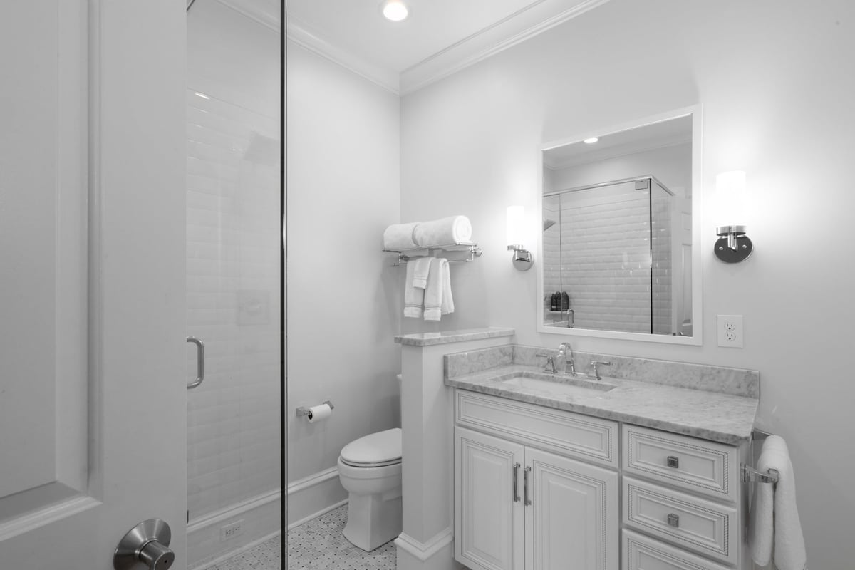 white bathroom with glass shower marble vanity and framed mirror in charlotte nc whole home remodel