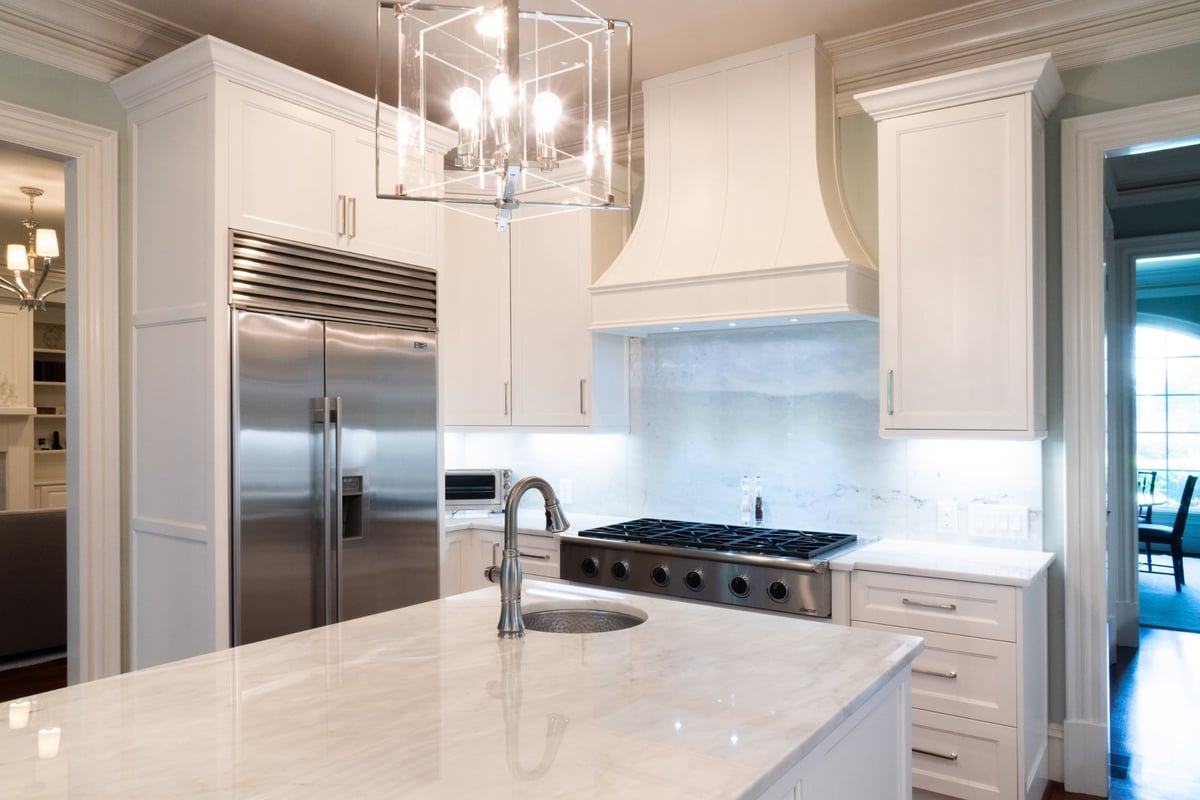 white kitchen with custom range hood stainless refrigerator and marble island in charlotte nc whole home remodel