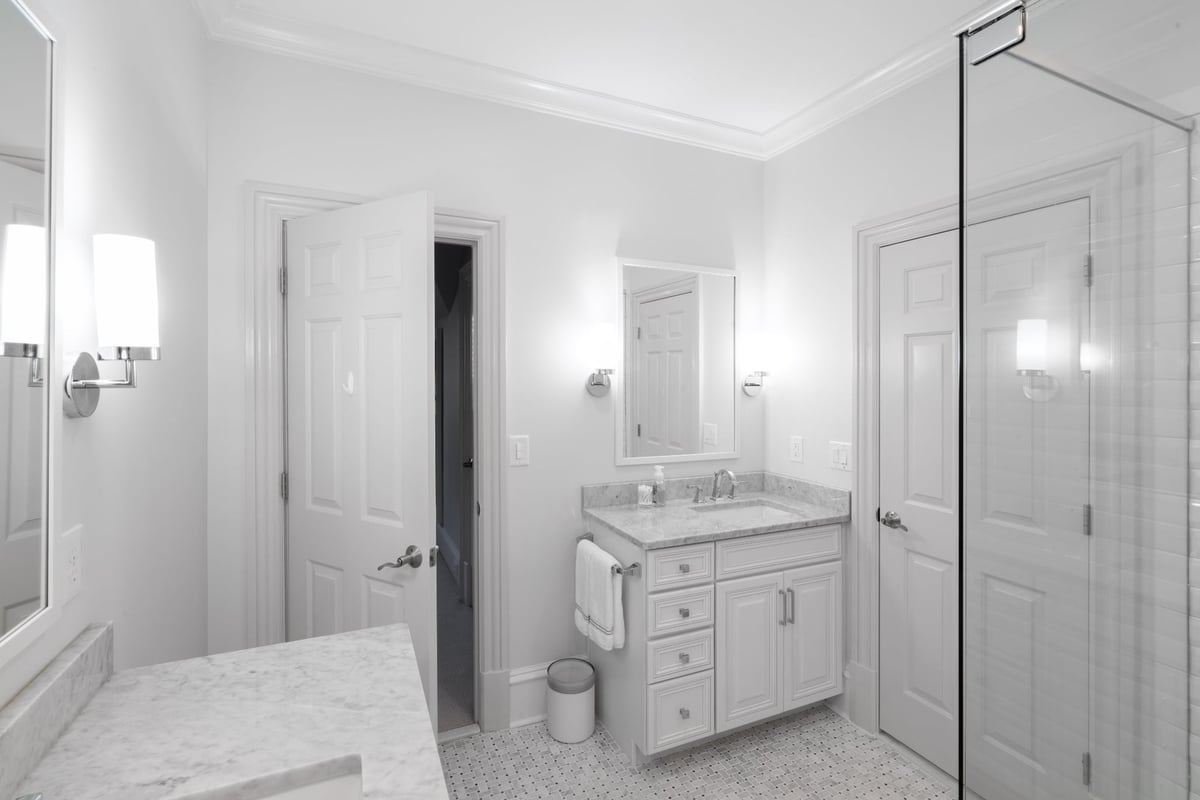 whole home remodel bathroom in charlotte nc with white vanity marble counter and glass shower enclosure