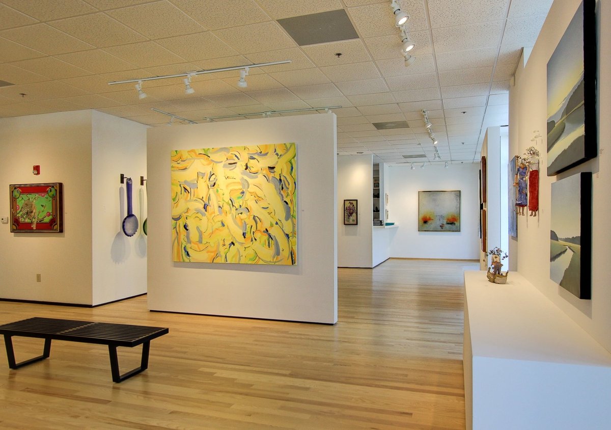 bright art gallery interior with yellow abstract painting and wood floors after a commercial remodel in charlotte nc
