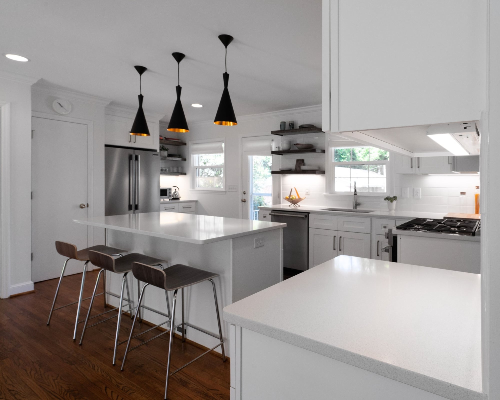 kitchen remodel with white island bar seating stainless refrigerator and black pendant lights in charlotte nc