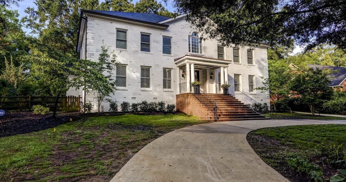 White brick two-story home with columned entry and landscaped front yard in Charlotte, NC.