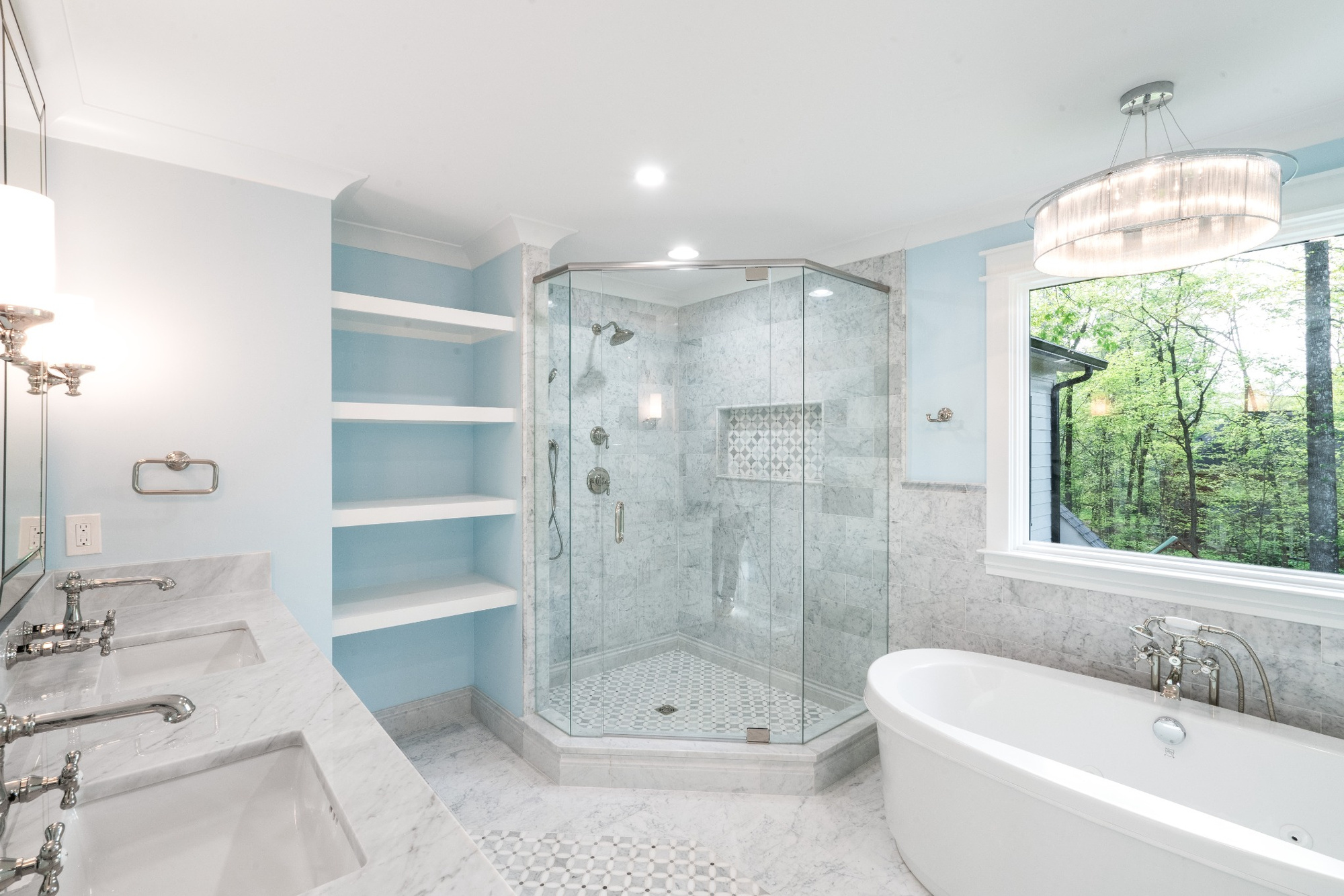 luxury primary bathroom with marble tile glass shower freestanding tub and blue walls in a custom home in charlotte nc