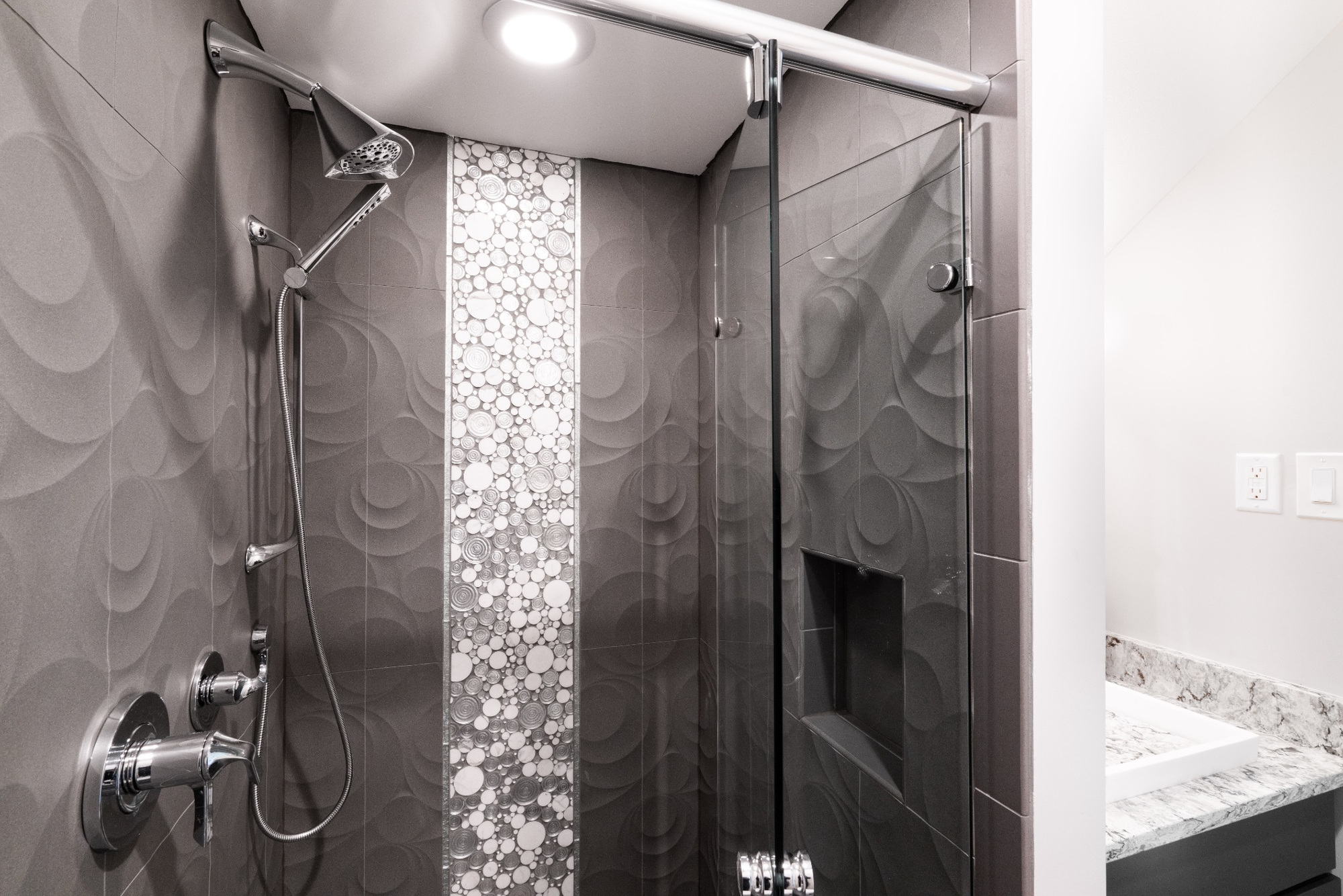 charlotte nc bathroom remodel shower with dark patterned tile pebble mosaic accent and chrome fixtures