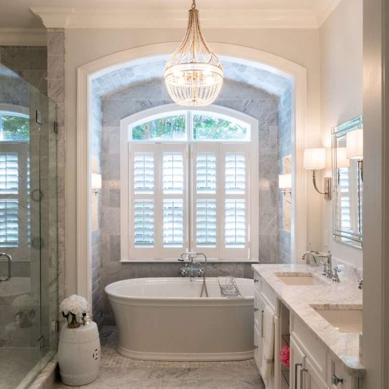 bathroom remodel with bathtub under a large window and marble tile done by 7 Acre construction