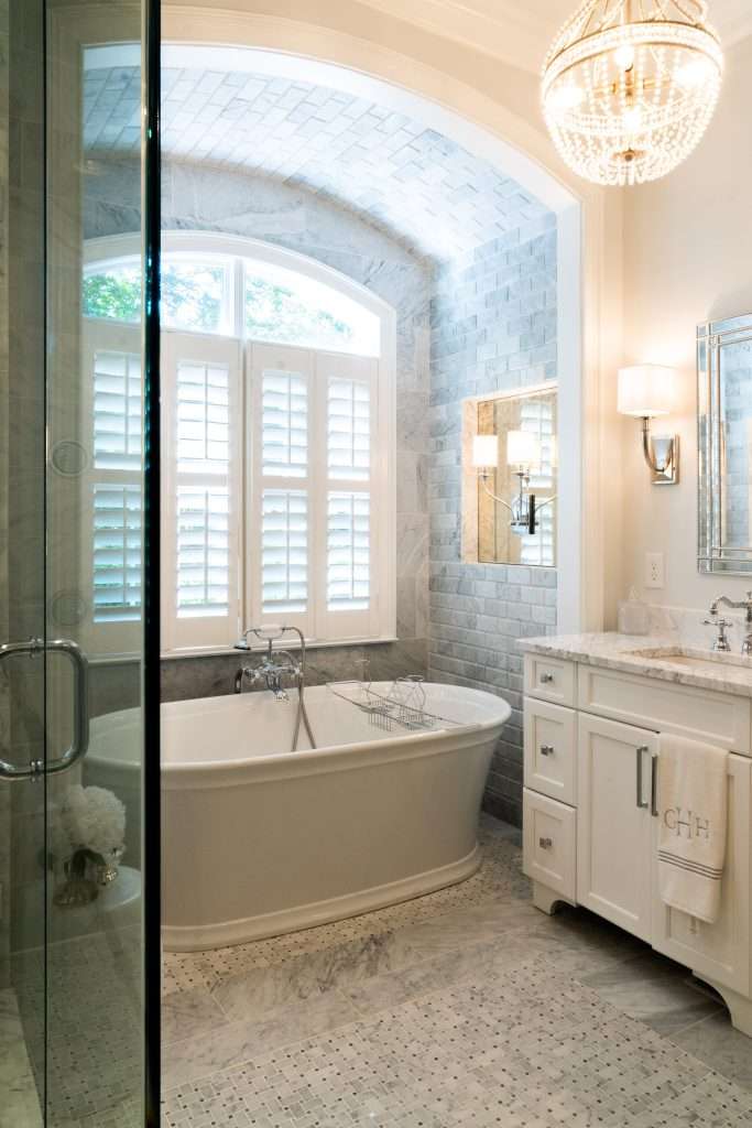 bright bathroom remodel with bathtub under a large window and marble tile done by 7 Acre construction