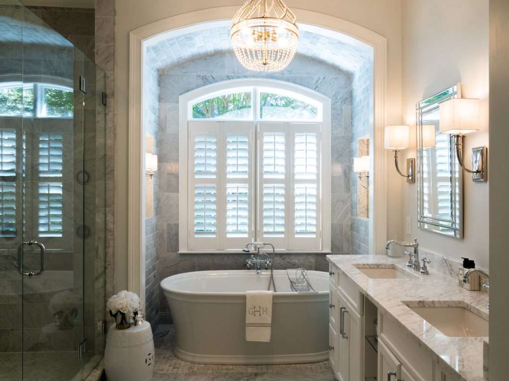 bathroom remodel with bathtub under a large window and marble tile done by 7 Acre construction