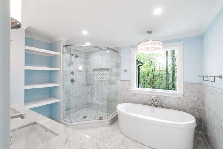 elegant bathroom remodel with free standing bathtub and separate shower stall with marble on walls and floor done by 7 acre construction
