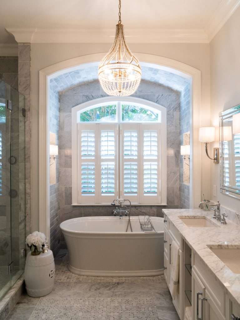 bright bathroom remodel with bathtub under a large window and marble tile done by 7 Acre construction