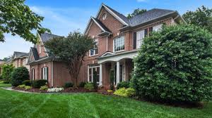 large brick house with trees and bushes in front